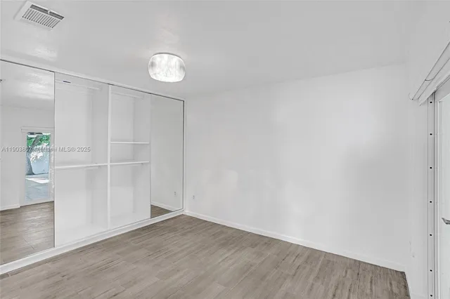 a view of empty room with wooden floor and window