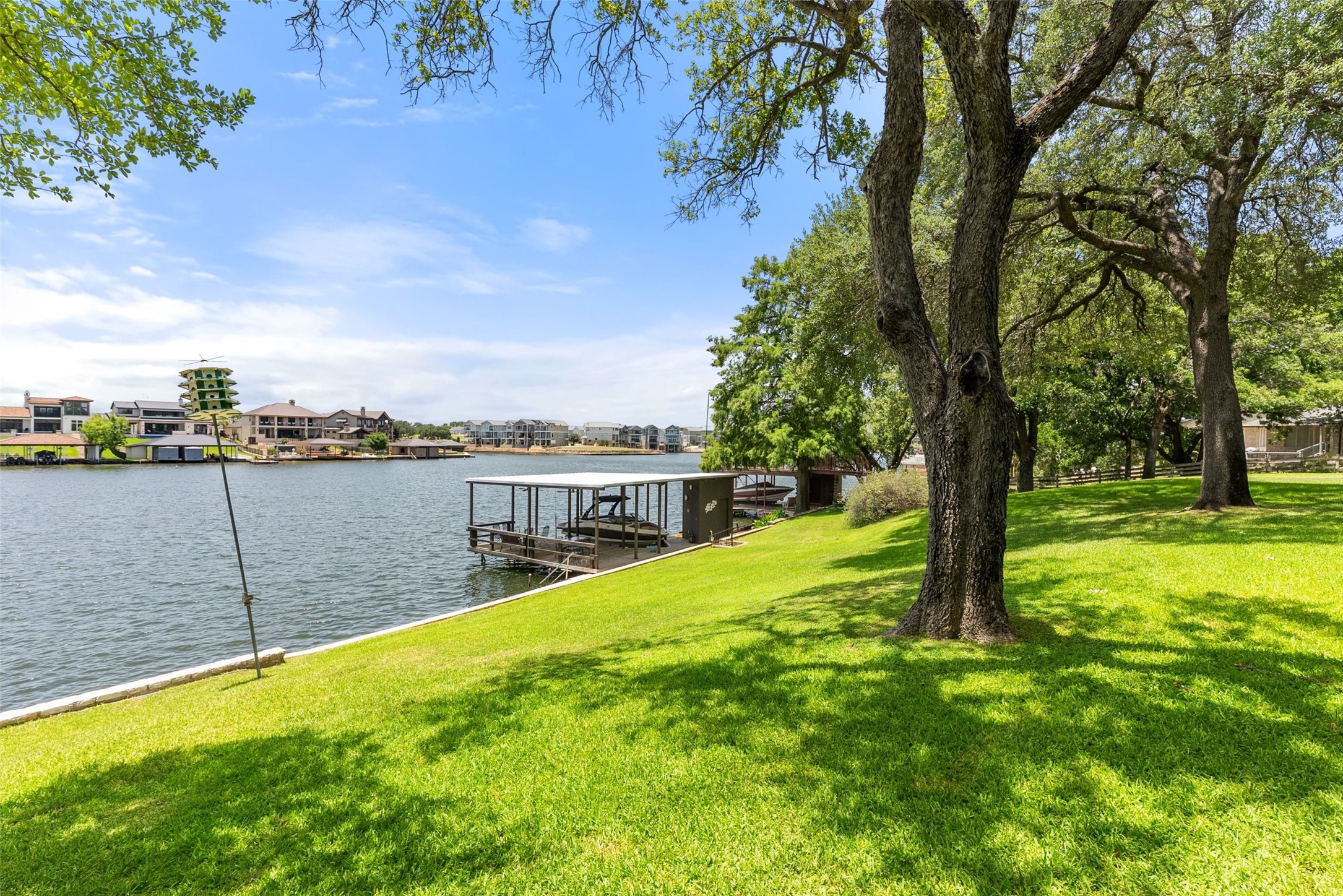 141 Perry Lane Kingsland, TX 78639 - Photo 5 of 40 A tranquil lakefront property featuring a private boat dock and lush green lawns shaded by mature trees.