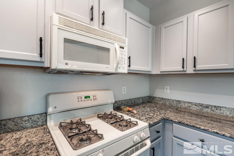 9050 Double R Boulevard Reno, NV 89521 - Photo 24 of 40 a kitchen with stainless steel appliances granite countertop a stove a microwave and cabinets