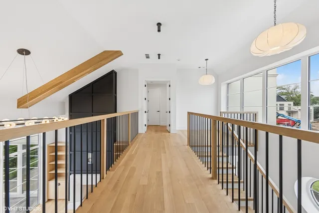 a view of a hallway with wooden floor and staircase