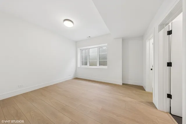 a view of an empty room with window and hardwood floor