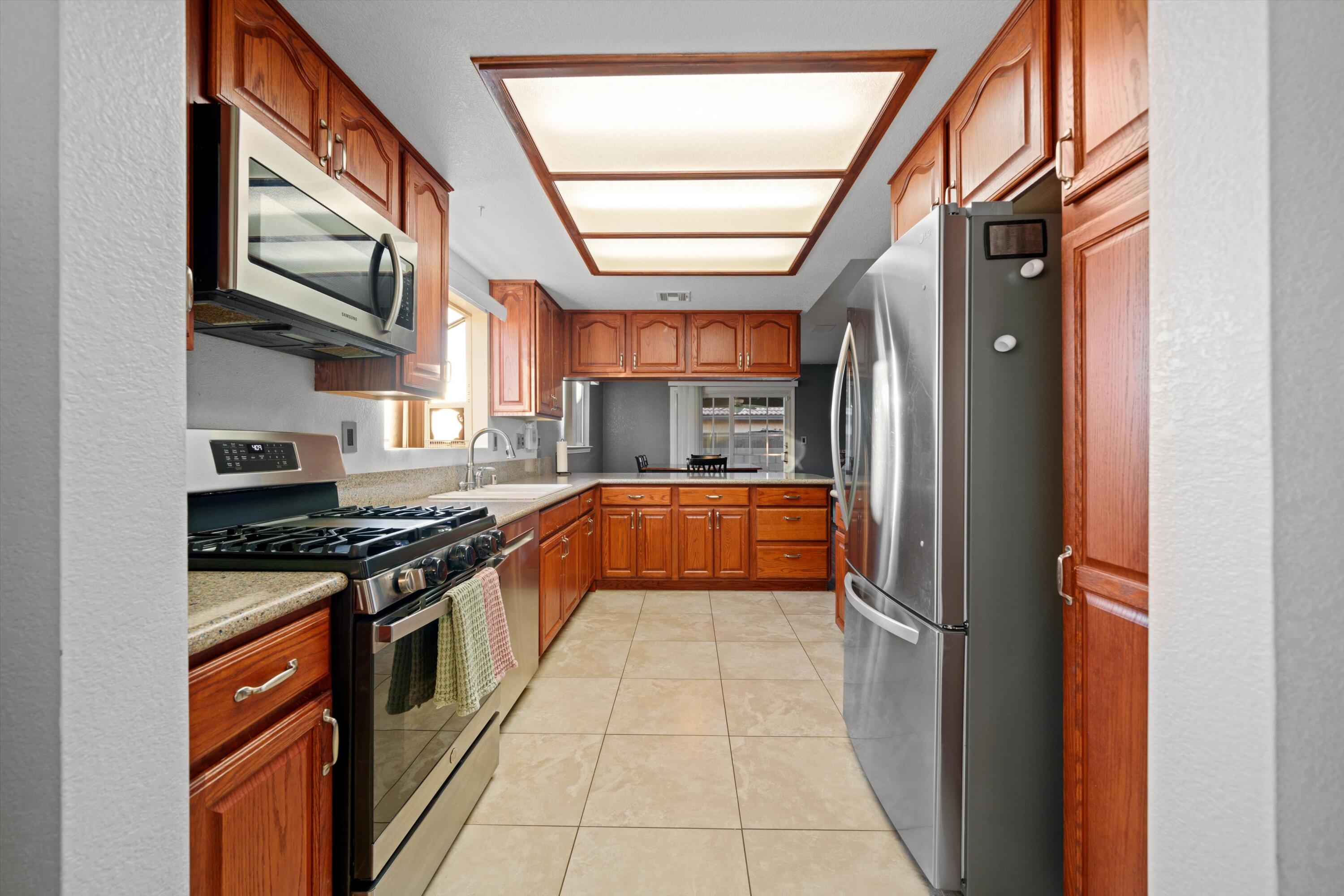 3525 West Roxbury Street Rosamond, CA 93560 - Photo 7 of 26 a kitchen with stainless steel appliances granite countertop a stove and a refrigerator
