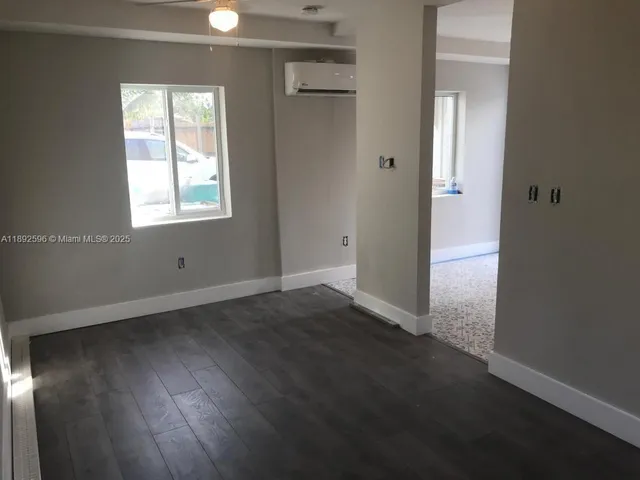 an empty room with wooden floor cabinet and windows