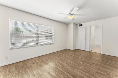 a view of an empty room with wooden floor and a window