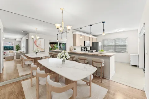 a kitchen with kitchen island a dining table chairs and white cabinets