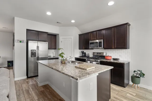 a kitchen with a sink a microwave a refrigerator and cabinets