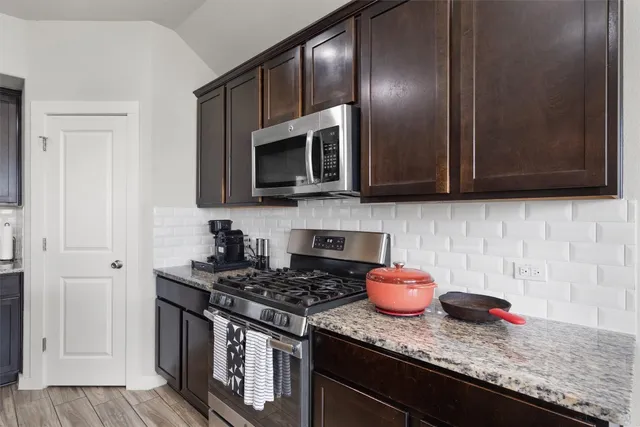 a kitchen with stainless steel appliances granite countertop wooden cabinets stove top oven and microwave