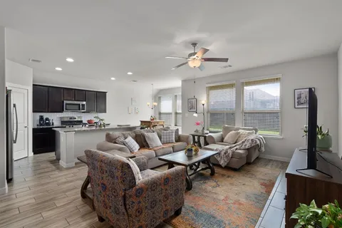 a living room with furniture kitchen view and a large window