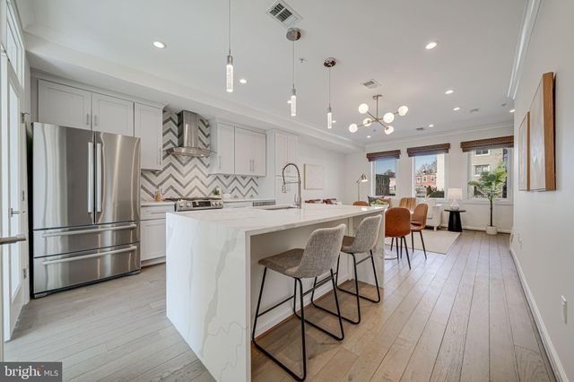 a kitchen with stainless steel appliances kitchen island granite countertop a refrigerator a stove a sink dishwasher and a dining table with wooden floor