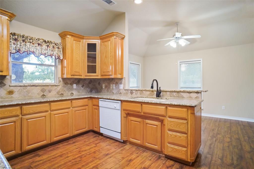 424 Half Moon Way Runaway Bay, TX 76426 - Photo 6 of 21 a kitchen with stainless steel appliances granite countertop a sink cabinets and wooden floor