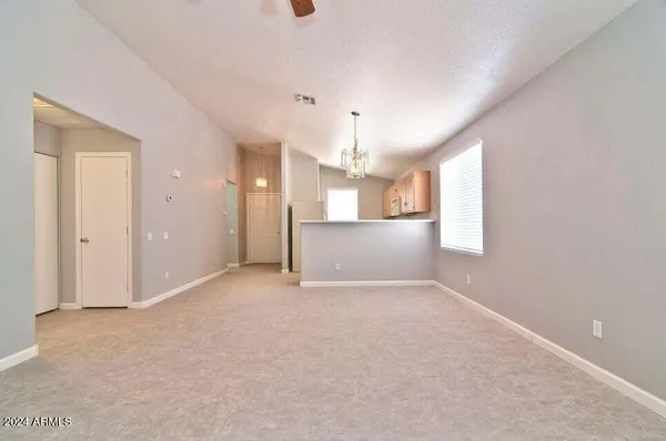 an empty room with a kitchen and a chandelier fan