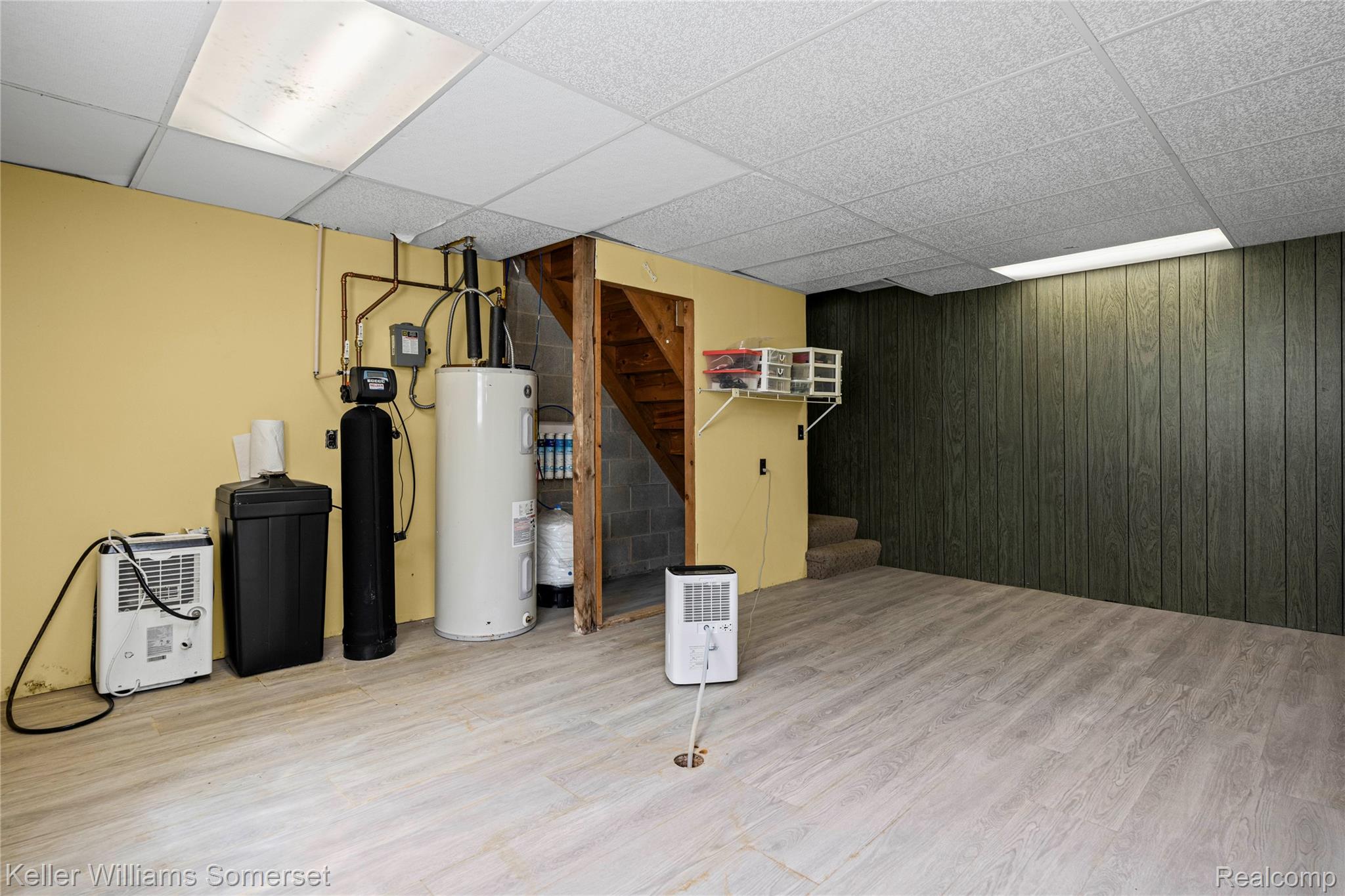 2344 Rochester Road Leonard, MI 48367 - Photo 37 of 66 Utility room featuring wood-finish flooring, drop-tile ceiling, exposed wooden stairs, water heater, and water filtration system