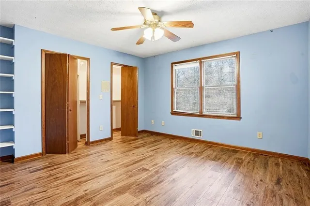 an empty room with wooden floor and windows