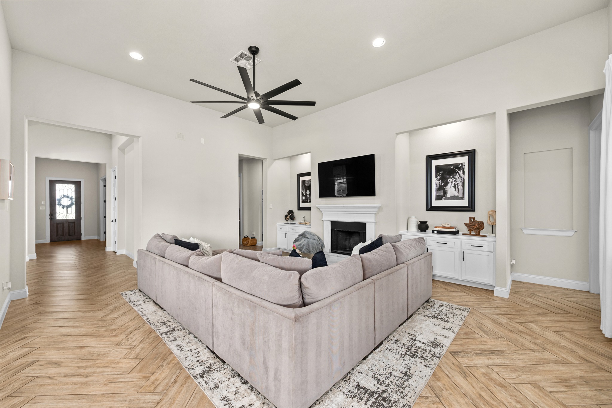2100 Highland Ridge Road Georgetown, TX 78628 - Photo 8 of 30 Herringbone pattern wood flooring grounds this open-concept living space, featuring a fireplace and recessed lighting.
