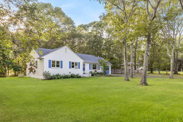a front view of a house with a yard and trees