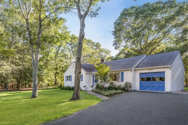 a front view of a house with a yard and trees