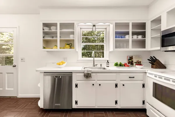 a kitchen with stainless steel appliances granite countertop a sink and a stove next to a window
