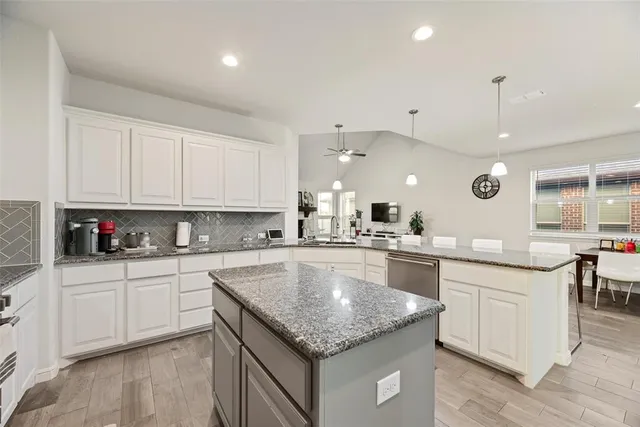 a kitchen with center island white cabinets and stainless steel appliances