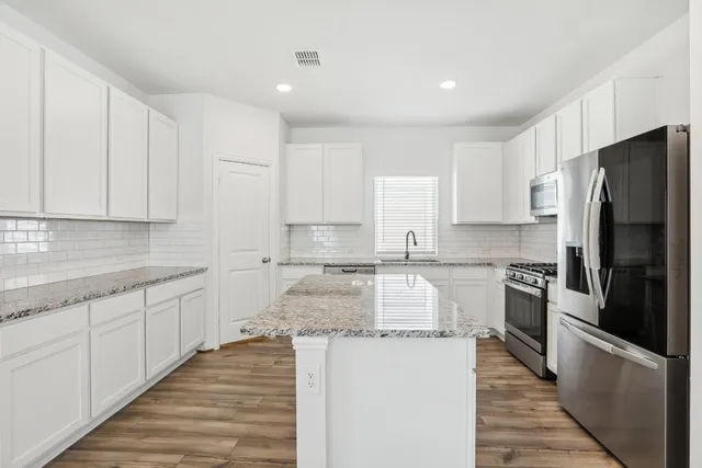 a kitchen with granite countertop white cabinets and stainless steel appliances