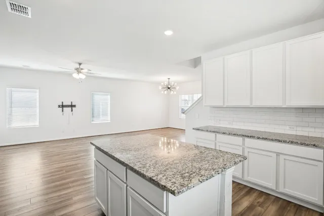 a kitchen with granite countertop a sink and white cabinets