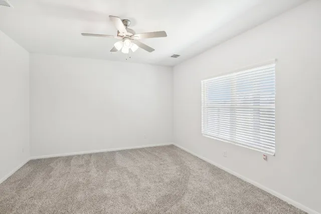 an empty room with a window and a fan