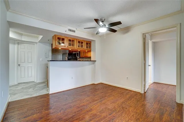 an empty room with wooden floor and a ceiling fan