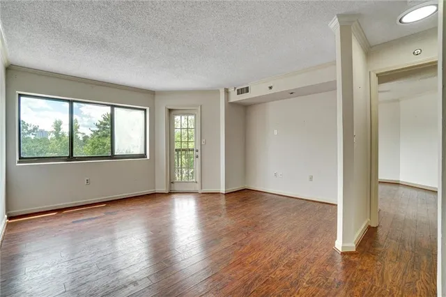 an empty room with wooden floor and windows