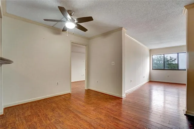 an empty room with wooden floor chandelier fan and windows