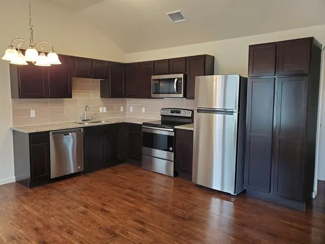 a kitchen with stainless steel appliances granite countertop a refrigerator a sink dishwasher a stove and a refrigerator