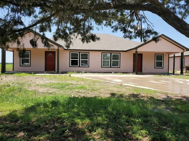 a front view of a house with yard and trees