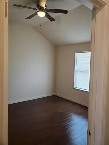 an empty room with wooden floor fan and windows