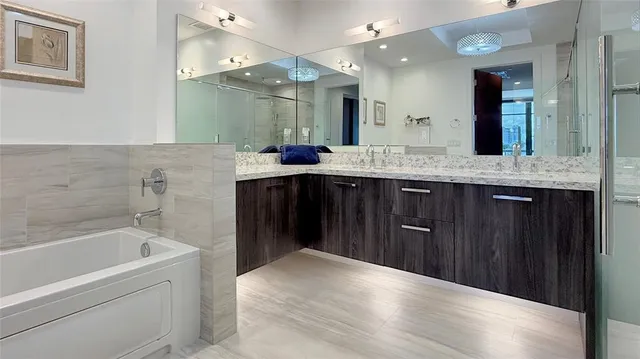 a spacious bathroom with a granite countertop sink a toilet a mirror a bathtub and shower