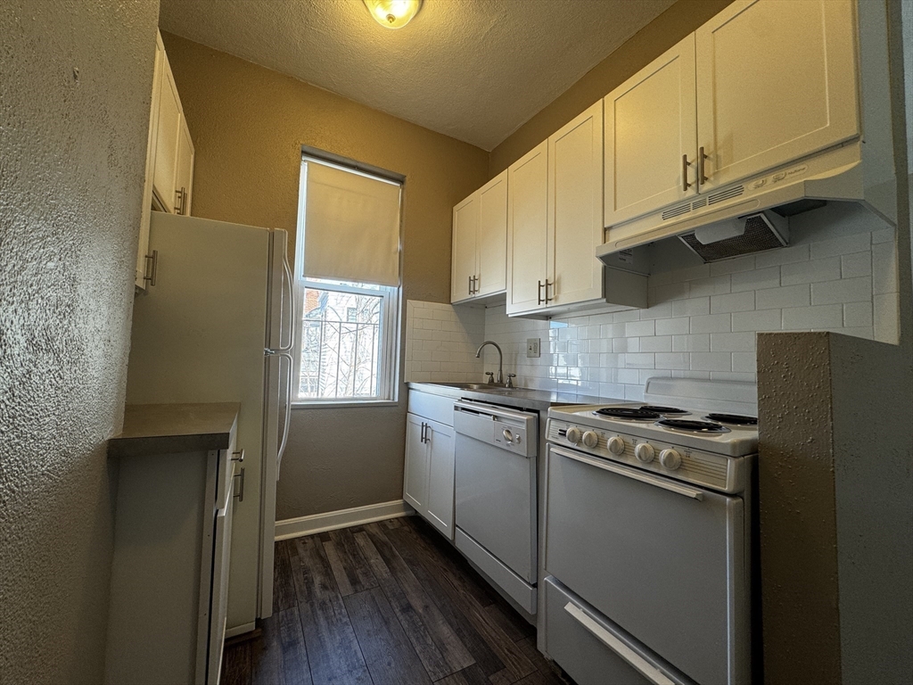 1870 Beacon Street, Unit 310 Brookline, MA 02445 - Photo 5 of 10 a kitchen with granite countertop cabinets stainless steel appliances and a window