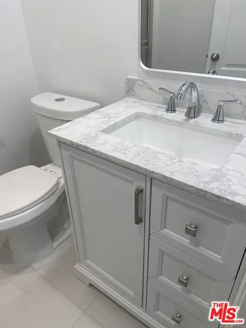 a bathroom with a granite countertop sink a toilet and a mirror