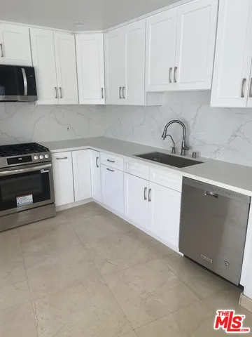 a kitchen with granite countertop white cabinets and stainless steel appliances