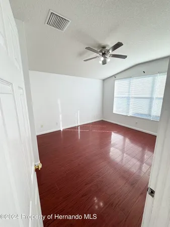 an empty room with windows and fan