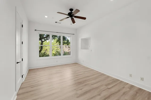 an empty room with a window and a ceiling fan