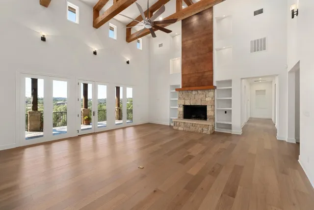 an empty room with wooden floor fan and windows