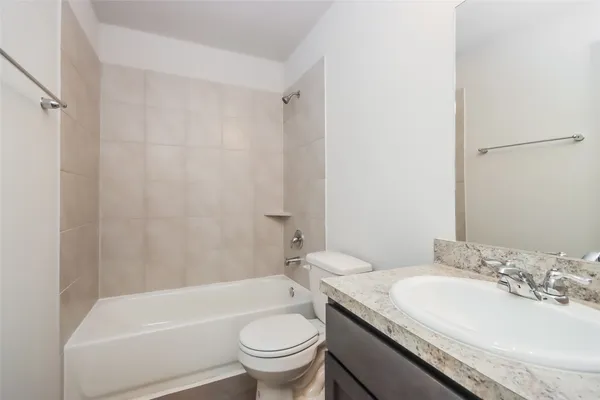 a bathroom with a granite countertop sink a toilet a mirror a bathtub and shower