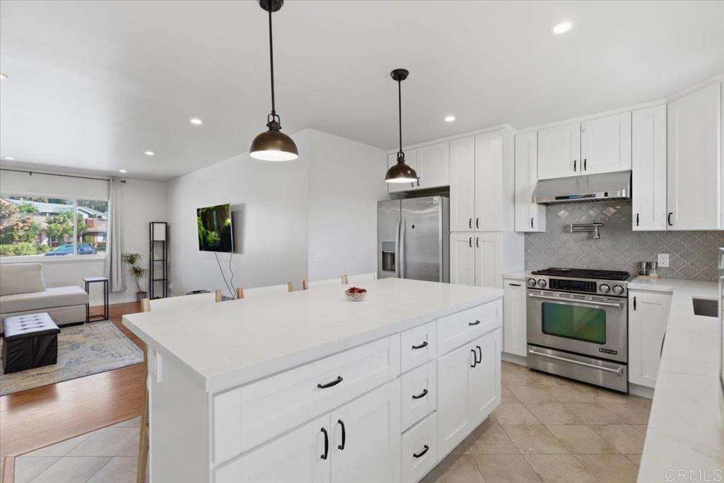 1915 Edith Drive Escondido, CA 92026 - Photo 3 of 41 a large kitchen with stainless steel appliances kitchen island granite countertop a stove a sink a dining table and chairs with wooden floor