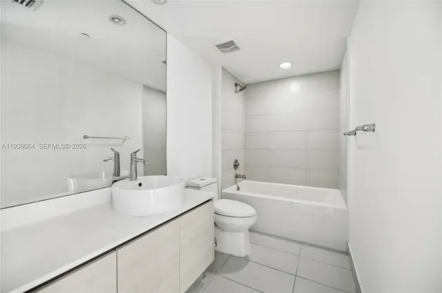 a bathroom with a bathtub shower sink vanity and toilet