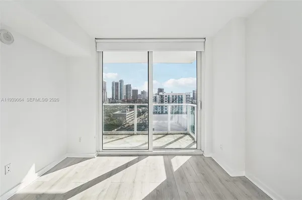 a view of an empty room with wooden floor and a window