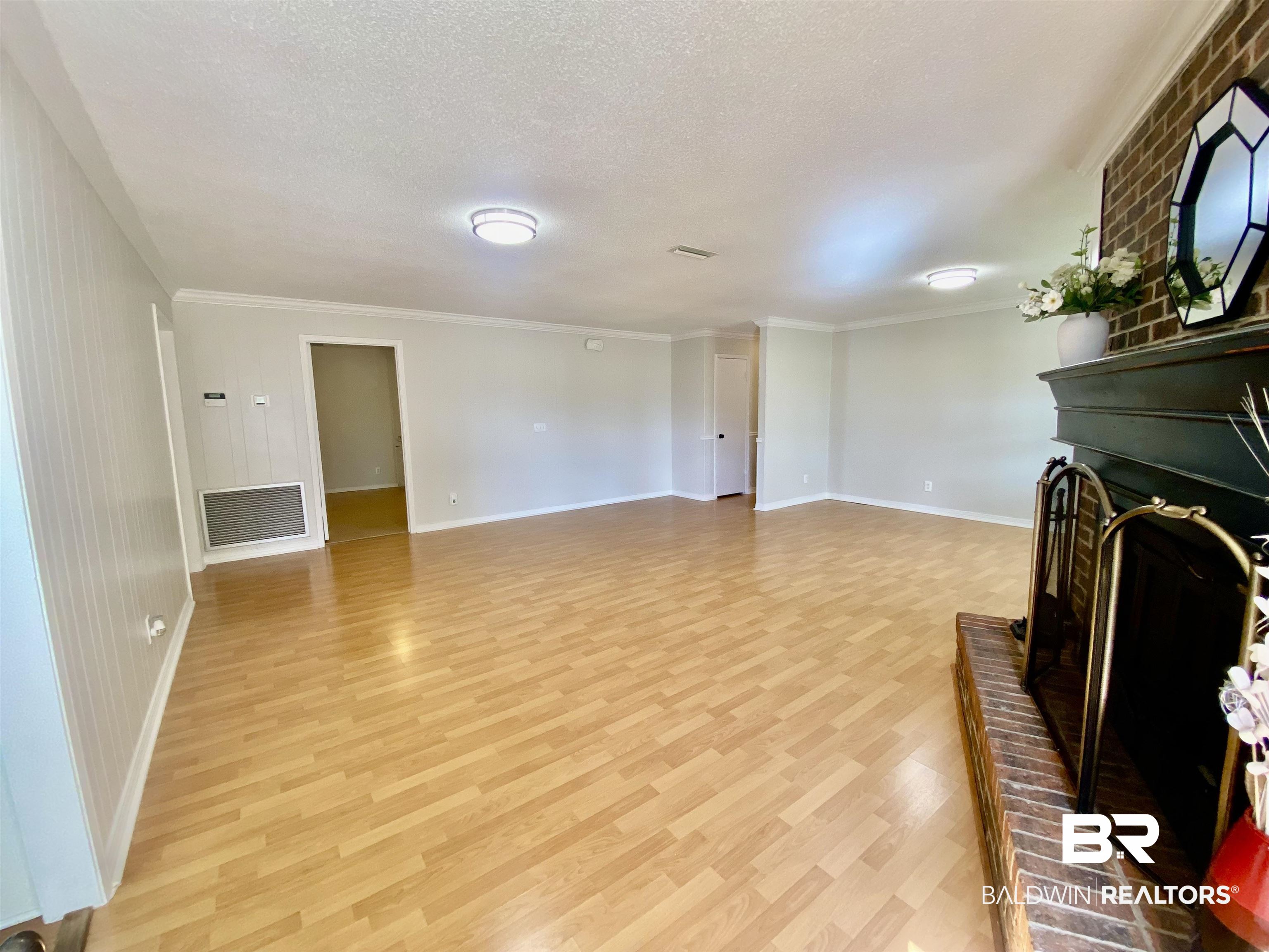 265 Azalea Drive Monroeville, AL 36460 - Photo 2 of 39 Unfurnished living room featuring ornamental molding, a fireplace, light hardwood / wood-style flooring, and a textured ceiling