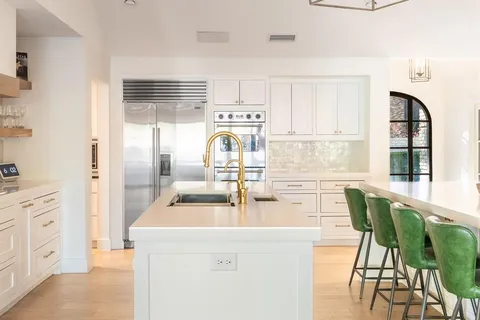 a kitchen with stainless steel appliances kitchen island granite countertop a table chairs sink and cabinets