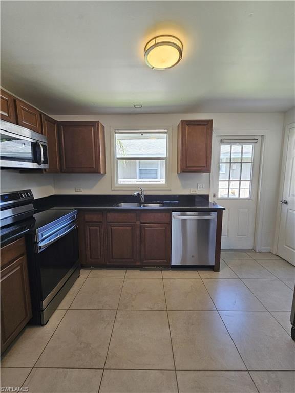 828 96th Avenue North, Unit B Naples, FL 34108 - Photo 5 of 13 Kitchen featuring stainless steel appliances, dark countertops, and light tile patterned floors