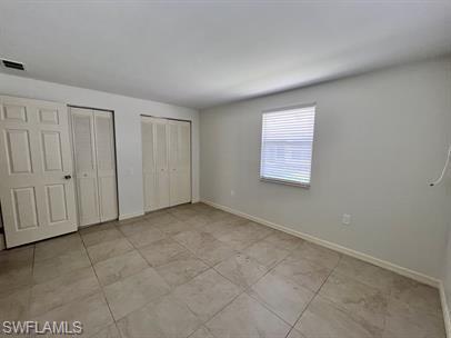 828 96th Avenue North, Unit B Naples, FL 34108 - Photo 9 of 13 Unfurnished bedroom with two closets, baseboards, and light tile patterned floors