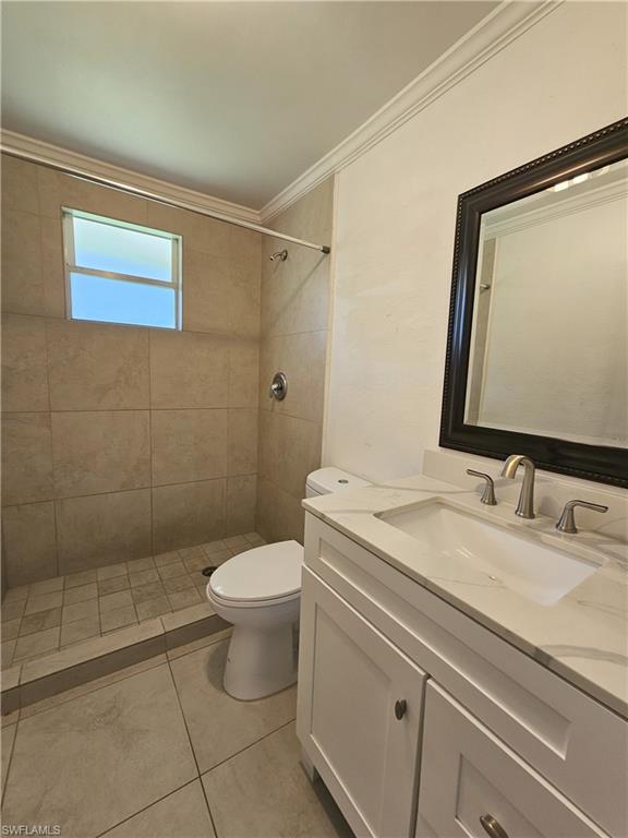 828 96th Avenue North, Unit B Naples, FL 34108 - Photo 10 of 13 Full bathroom featuring crown molding, vanity, a tile shower, and tile patterned floors