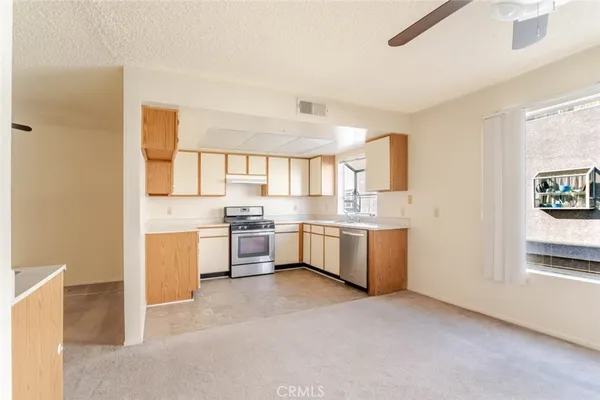 a large white kitchen with a sink a window and stainless steel appliances