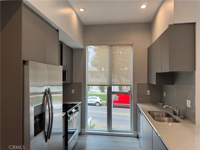 a kitchen with stainless steel appliances granite countertop a refrigerator a stove and a sink