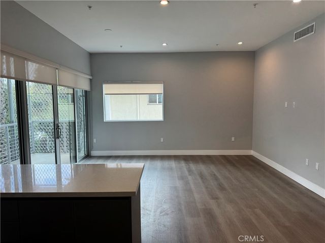 a view of open kitchen with kitchen island a sink wooden floor and a living room view